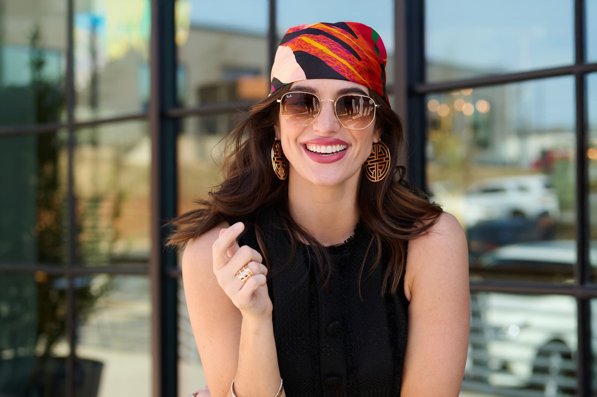 Smiling model wearing oversized gold statement earrings and gold rings
