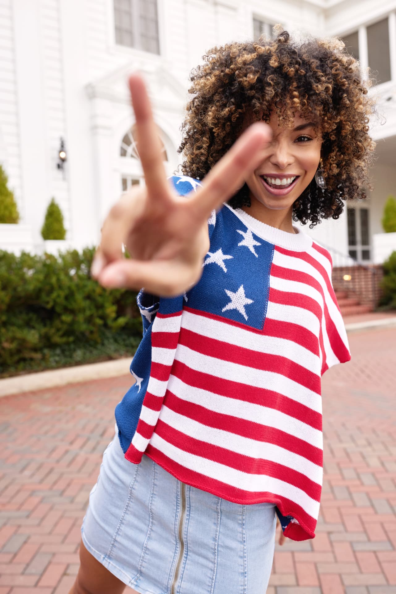 Model in a stars and stripes knit top wearing sparkling drop earrings